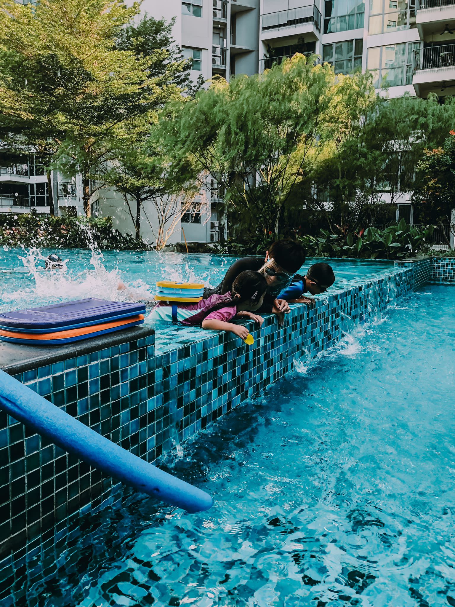 Kids splashing during a group swimming lesson at a condo pool
